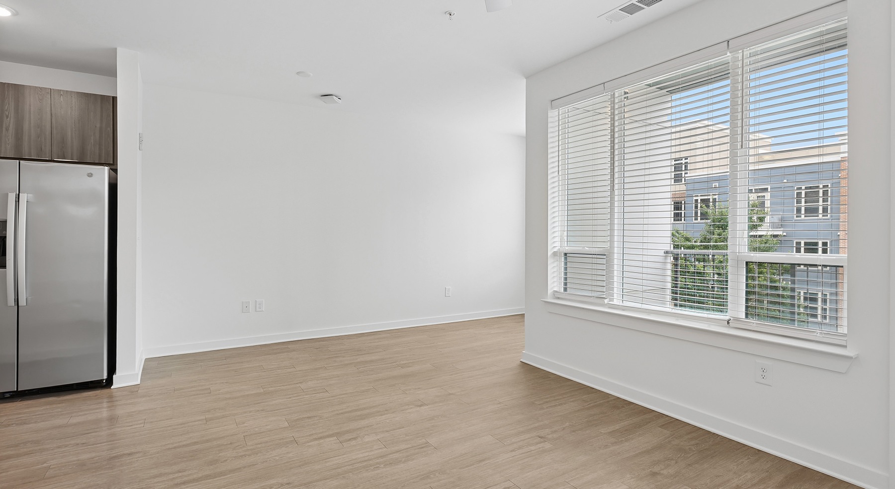 room with white walls wood floors and three windows